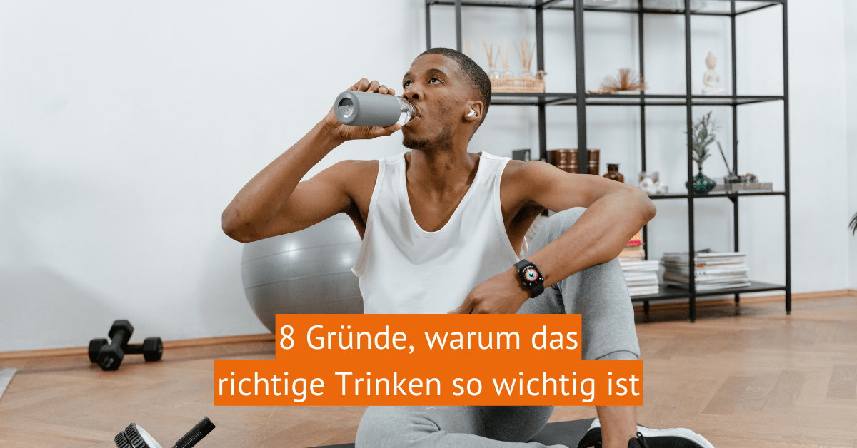 Ein dunkelhäutiger junger Mann sitzt auf dem Boden und trinkt aus einer Trinkflasche. Hinter ihm ist ein schwarzes Metallregal mit Dekorationen und um ihm herum ein paar Hanteln, ein großer Gummiball und eine Bauchtrainingsgerät.