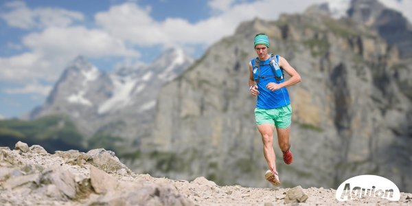 Leistungssportler läuft durch die Berge. Sportlerwasser von Aquion ist das Thema