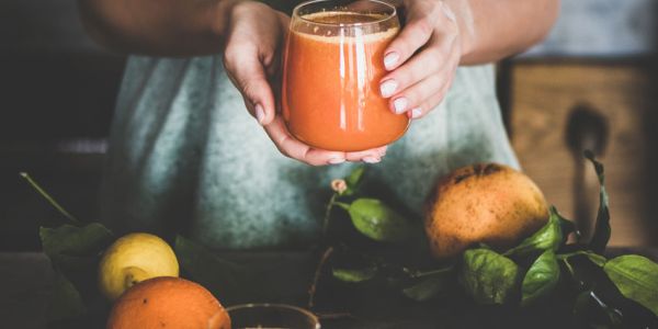Frau mit Glas in der Hand und mit Nektarinen vor sich